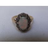 18ct gold firey oval opal with diamond surround size K / L