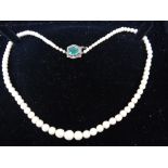 Small string of graduated pearls with emerald coloured stone to clasp