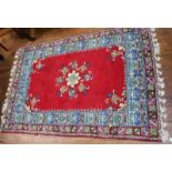 A handmade Moroccan carpet with floral central medallion to a red ground, blue patterned inner