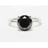 An 18ct white gold four claw set black diamond solitaire ring, the diamond approximate weight 2.98