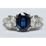 A large diamond and sapphire three stone ring, set with central oval sapphire weighing approx 1.5