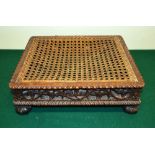 A nineteenth century Anglo Indian carved hardwood foot stool, with a caned seat, a pierced foliage c