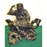 A nineteenth century Japanese bronze of an Oni, with detachable head, holding a staff, seated on a b