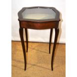 An Edwardian mahogany bijouterie, the square top serpentine sided, having a glazed hinged lid,