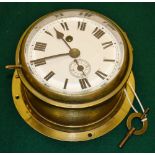 An early twentieth century brass bulkhead clock, a circular white enamel dial with Roman numerals, s