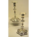 A pair of George II cast candlesticks, with shaped circular six shell welled bases engraved an