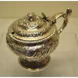 A George IV silver mustard pot, the ogee body and hinged cover chased with repouse foliage, having a