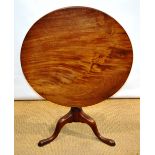 A George III mahogany occasional table, the circular well figured tilt top on a baluster turned