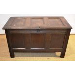 A seventeenth century panelled oak coffer, the hinged lid reveals a lidded candlebox, the front