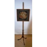 A Regency mahogany pole firescreen, with a needlework panel, the ring turned stem base on three