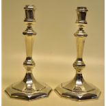 A pair of George 1st style silver cast octagonal candlesticks, with baluster stems and campanula