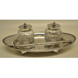 An Edwardian silver navelette shape inkstand, having a gadroon border, and two cut glass oval ink