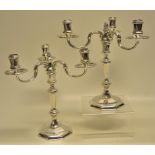 A pair of George 1st style cast silver octagonal three light candelabra, on scroll branches, campana