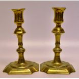 A pair of mid eighteenth century brass candlesticks, with knopped stems on welled square bases