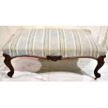 A large Victorian stool, the upholstered serpentine edge seat with carved foliage to the border,