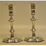 A pair of George II silver cast candlesticks, the spool shape candleholders with extension