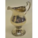 A George III silver inverted pear shape cream jug, with a gadroon edge lip, a leaf capped scroll