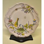 A French Faience plate, the mushroom ground painted a bird on a pomegraint bough with flowers and