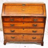 An early nineteenth century oak bureau, the front mahogany cross banded with stringing, the fall