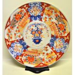 A late nineteenth century Japanese Imari porcelain charger, decorated in rust blue and green, an urn