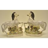 A pair of Victorian Staffordshire zebras, prancing on a mossy bank. 9in (23cm).