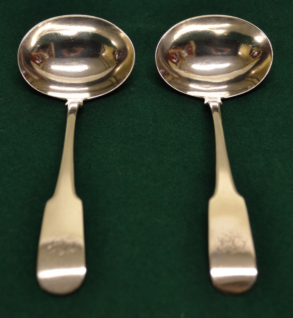 A pair of Regency Irish silver fiddle pattern sauce ladles, engraved initials, with oval bowls.