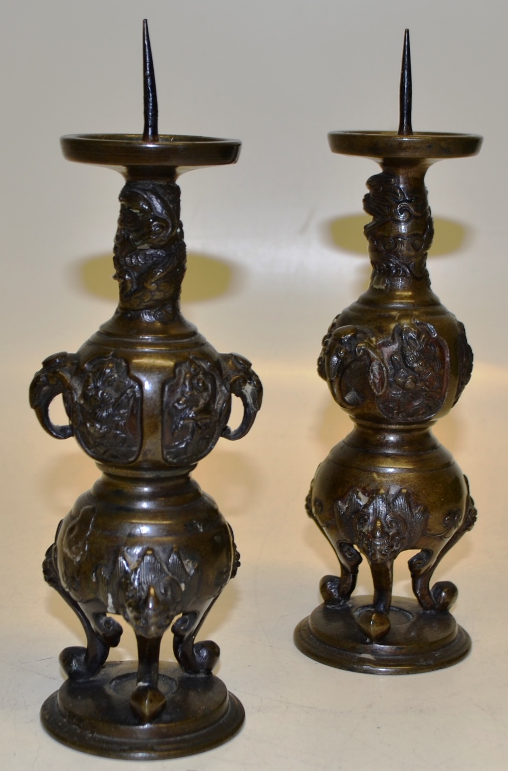A pair of Japanese late nineteenth century bronze candlesticks, with iron prickets to the