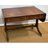 A Regency mahogany sofa table, the rectangular drop leaf top, cross banded in maccasser ebony with