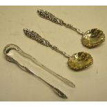 A pair of mid nineteenth century Russian silver rococo chased sugar tongs, Moscow 1856 and a later