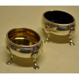 A pair of George III oval silver salts, gilded inside with gadroon borders, on shell appliqué legs