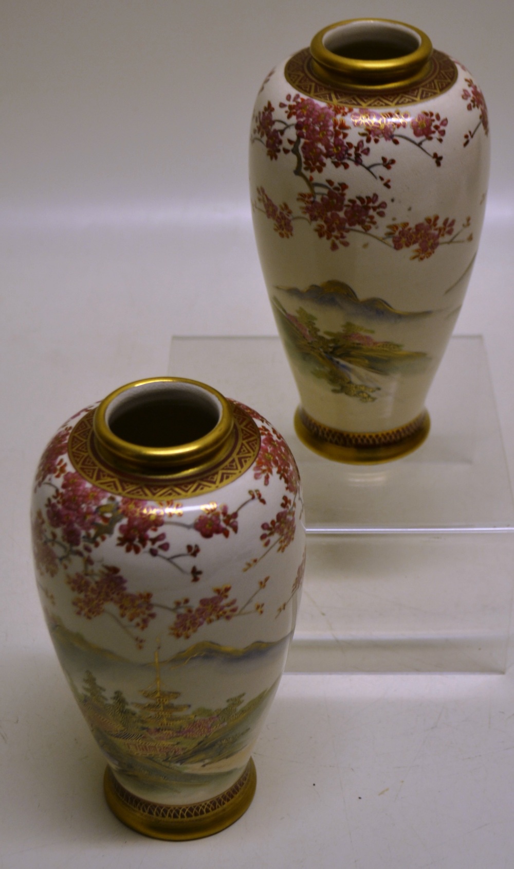 A pair of Japanese satsuma ovoid vases, decorated pagodas in a mountainous landscape, with gilt,