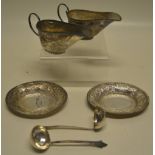 A pair of Burmese silver coloured metal oval sauce boats and stands, with chased foliage decoration,