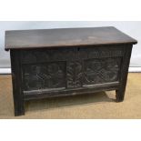 A seventeenth century oak coffer, the moulded edge planked lid on iron hinges, a leaf lunette carved