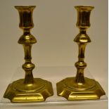 A pair of eighteenth century brass candlesticks, with knopped stems on welled square bases with cusp