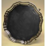 A circular silver salver, with a raised moulded serpentine border and four hoof feet. 10in (26cm)