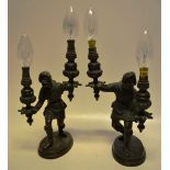 A pair of nineteenth century bronze candelabra, of Medieval figures of woodsmen supporting twin
