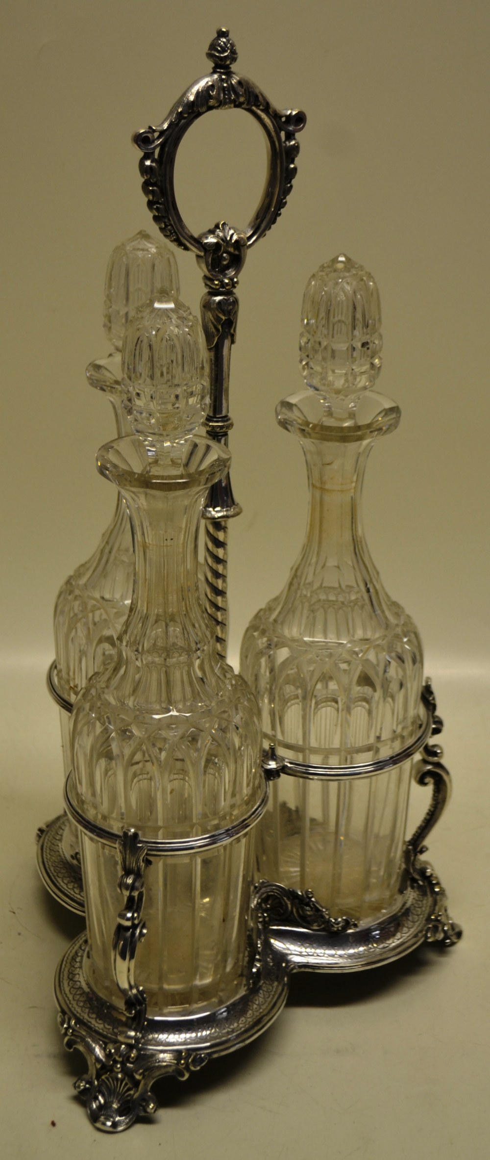 A Victorian electroplated tantalus with three cut glass decanters with stoppers, in a triform