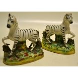 A pair of nineteenth century Staffordshire zebras, (ears chipped), standing on a green splash