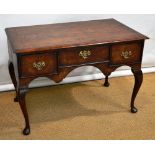 A walnut veneered writing table, the feather banded top above a shaped frieze with three drawers,