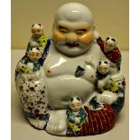 A Chinese porcelain hotei figure surrounded by little children, their clothing decorated in coloured