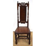 An oak high back side chair, the fielded panelled high back with a scrolling crown crest and