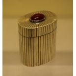 A modern designer silver oval box, with reeded decoration, the detachable cover with a cabouchon