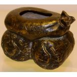 A Japanese nineteenth century bronze pot, of a tied open side sack, laid onto two bales, four