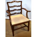 A George III mahogany elbow chair, the pierced ladderback with outscrolling arms to a drop in