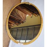 A Victorian large oval mirror, in a gilt plaster foliage frame with remains of a ribbon surmount.