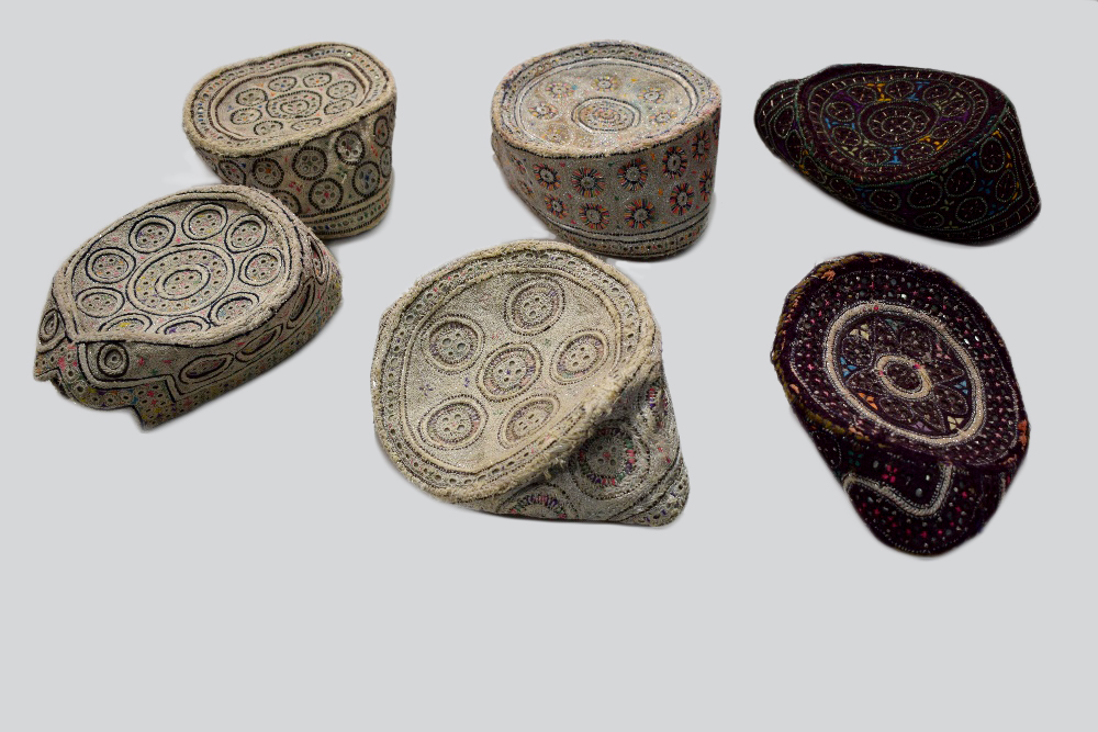 Six Sindhi Baluchi topi (caps), embroidered in coloured silks, metal threads and shisha-work (