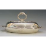 A silver entrée dish of oval form with stylised scroll detailing to borders, conforming handle,