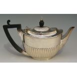 A small silver teapot, half lobed body and hinged lid, ebonised handle and finial,