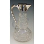 A claret jug with plain silver collar, handle and hinged lid, the body diamond and facet cut glass,