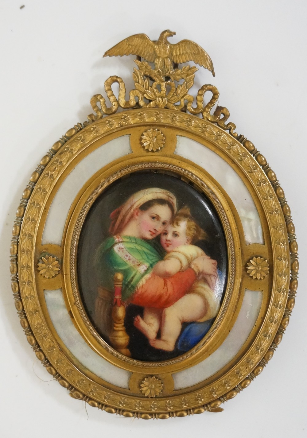 A continental oval porcelain plaque decorated with Madonna and child contained within an ornate
